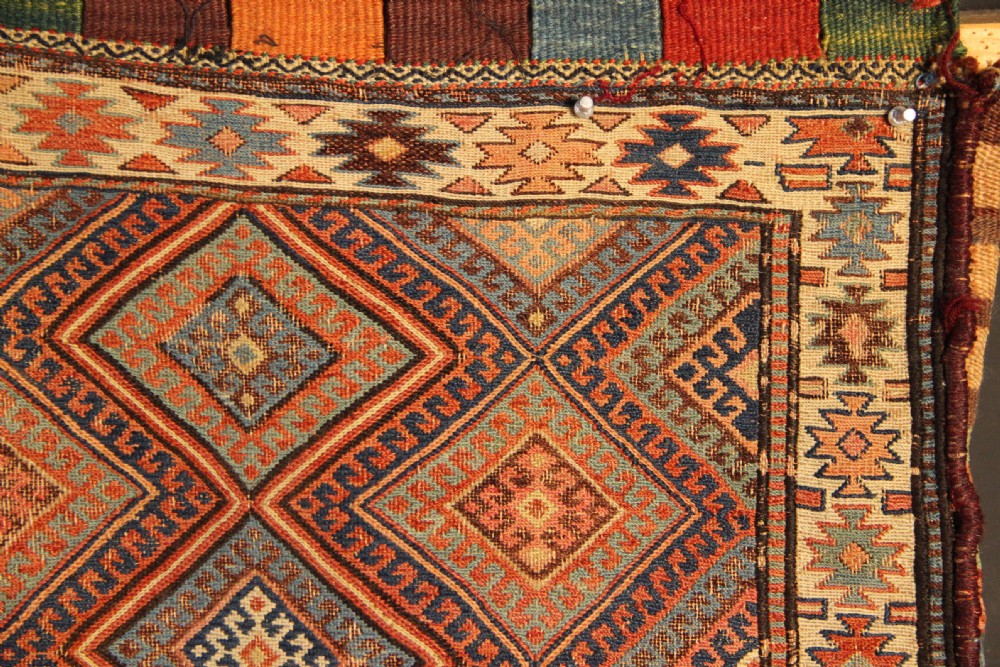 An antique square Shahsavan Soumac woven saddlebag face featuring geometric diamond medallions in terracotta red, navy, and soft blue wool. View II