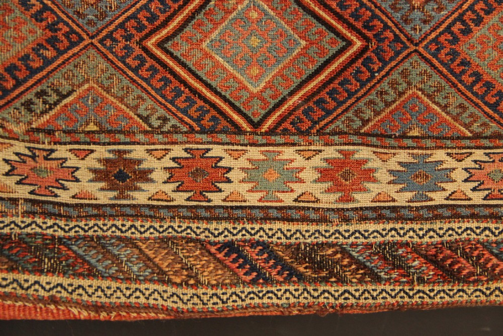 An antique square Shahsavan Soumac woven saddlebag face featuring geometric diamond medallions in terracotta red, navy, and soft blue wool. View III