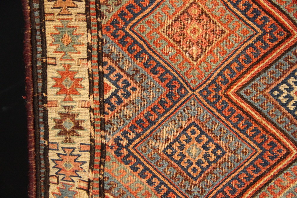 An antique square Shahsavan Soumac woven saddlebag face featuring geometric diamond medallions in terracotta red, navy, and soft blue wool. View V