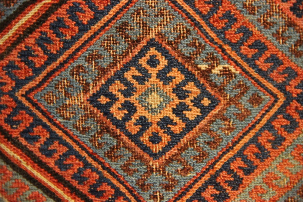 An antique square Shahsavan Soumac woven saddlebag face featuring geometric diamond medallions in terracotta red, navy, and soft blue wool. View VI