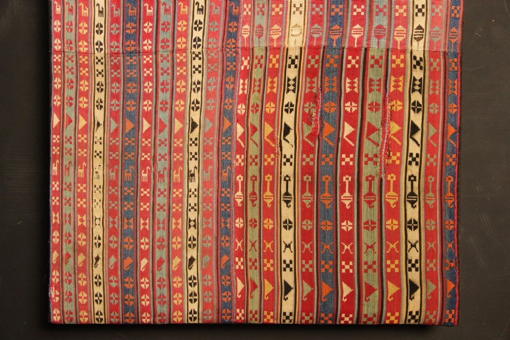A rectangular mounted 19th-century silk jajim textile featuring vertical stripes with intricate geometric and stylized animal motifs in red, blue, cream, and yellow hues. View III