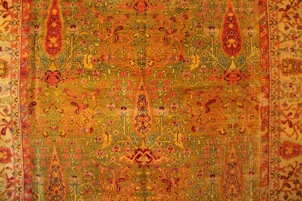 A large hand-knotted wool carpet featuring mustard yellow, olive green, and terracotta red tones with detailed floral and paisley motifs throughout. View II