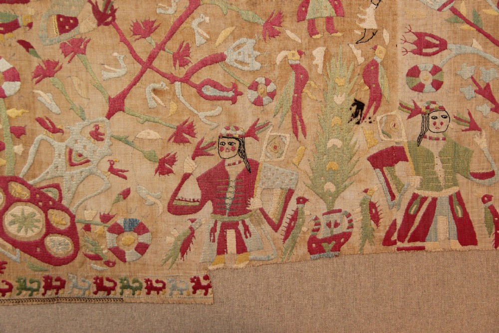An antique hand-embroidered linen textile fragment from Skyros featuring red and green silk threads depicting human figures, birds, and floral motifs. View II