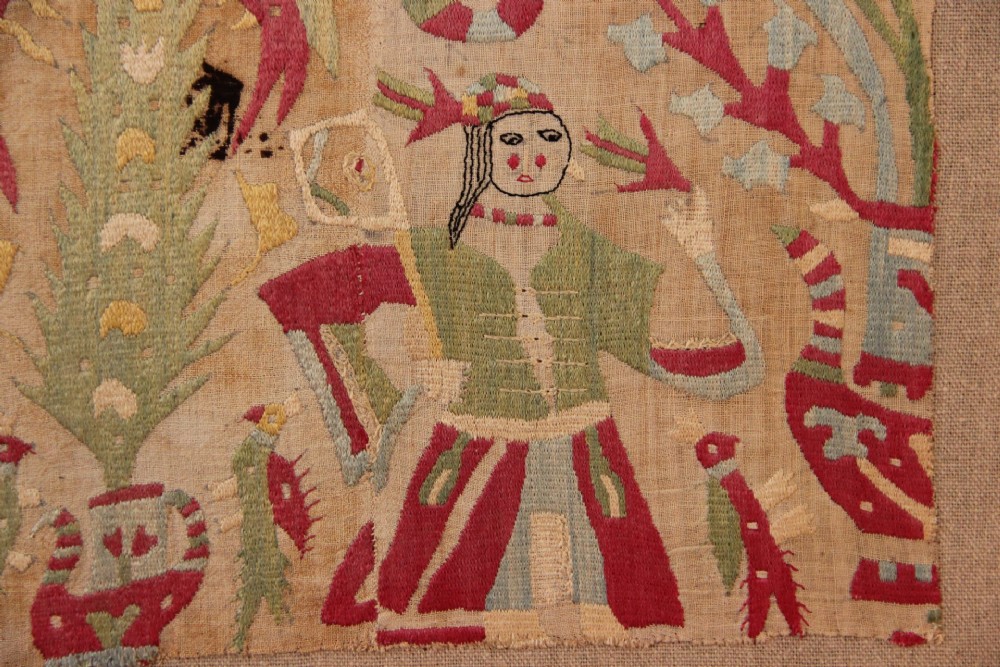An antique hand-embroidered linen textile fragment from Skyros featuring red and green silk threads depicting human figures, birds, and floral motifs. View III