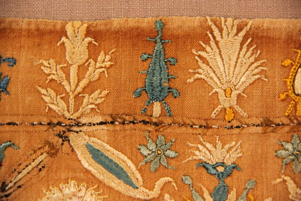An 18th-century rectangular Cretan textile panel featuring polychrome silk embroidery on a natural beige linen ground with repeating geometric lattices, stylised human figures, birds, and floral motifs. View V