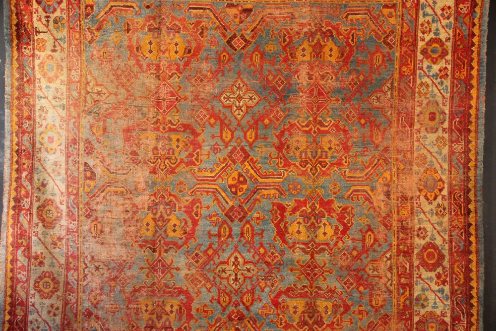 A large antique Turkish Oushak wool carpet featuring a pale blue field layered with terracotta and gold medallion motifs and a patterned border. View II