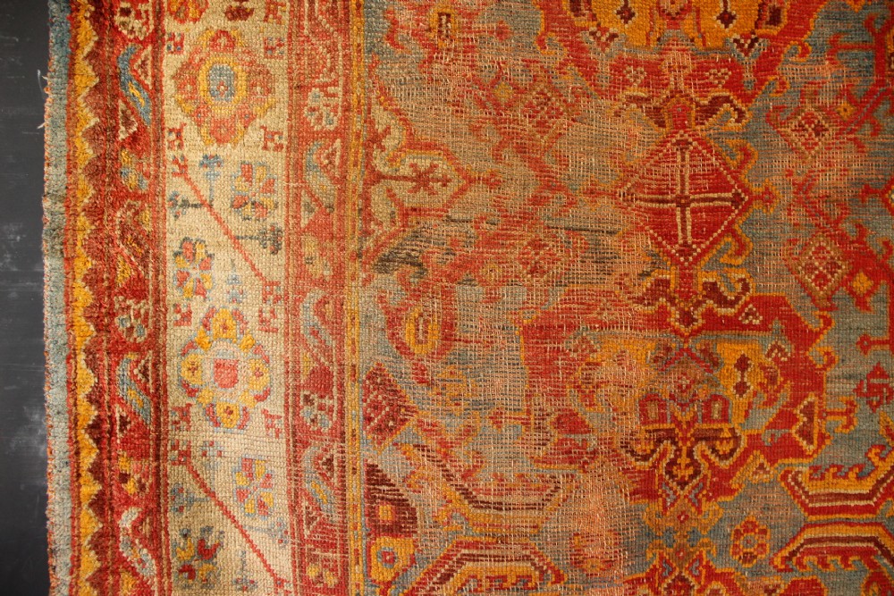 A large antique Turkish Oushak wool carpet featuring a pale blue field layered with terracotta and gold medallion motifs and a patterned border. View V