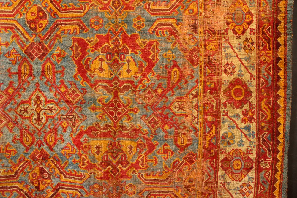 A large antique Turkish Oushak wool carpet featuring a pale blue field layered with terracotta and gold medallion motifs and a patterned border. View VII