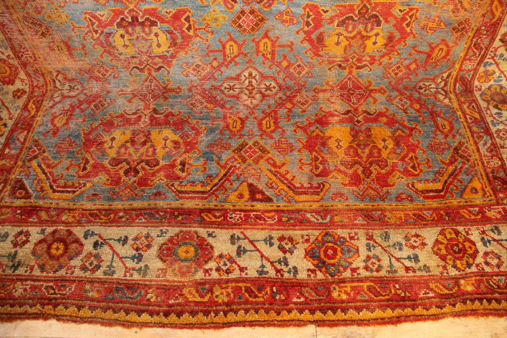 A large antique Turkish Oushak wool carpet featuring a pale blue field layered with terracotta and gold medallion motifs and a patterned border. View VIII
