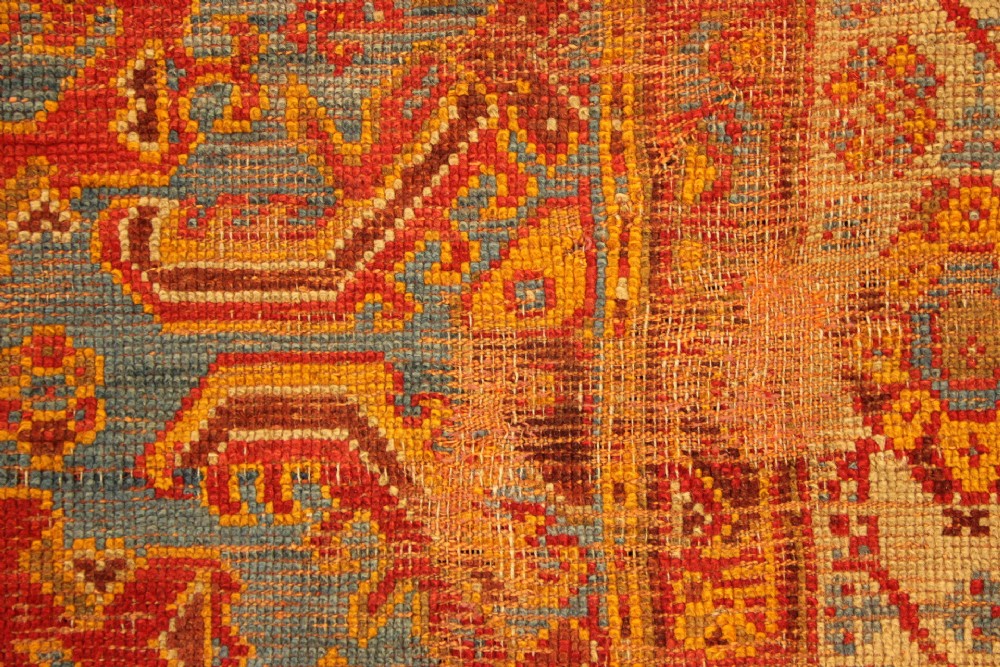 A large antique Turkish Oushak wool carpet featuring a pale blue field layered with terracotta and gold medallion motifs and a patterned border. View X