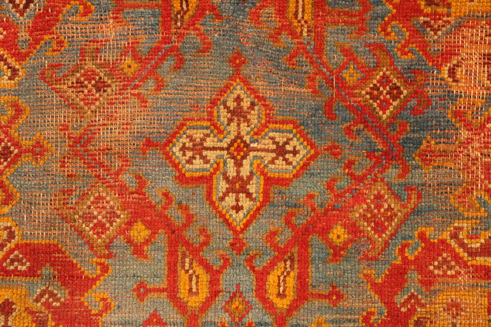 A large antique Turkish Oushak wool carpet featuring a pale blue field layered with terracotta and gold medallion motifs and a patterned border. View XI