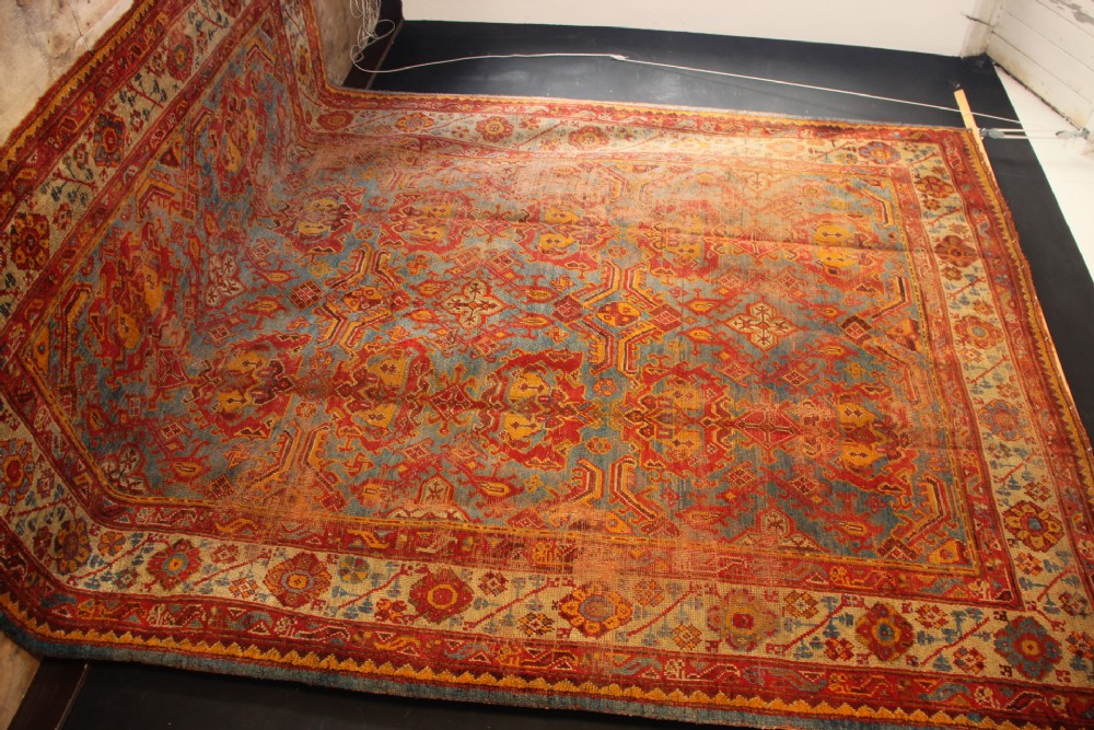 A large antique Turkish Oushak wool carpet featuring a pale blue field layered with terracotta and gold medallion motifs and a patterned border. View XIII