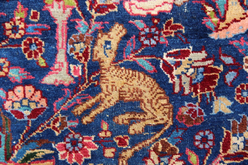 A large hand-knotted Persian Tabriz carpet featuring a central cream medallion surrounded by a navy blue field with intricate floral and hunting motifs, framed by a detailed red border. View VIII