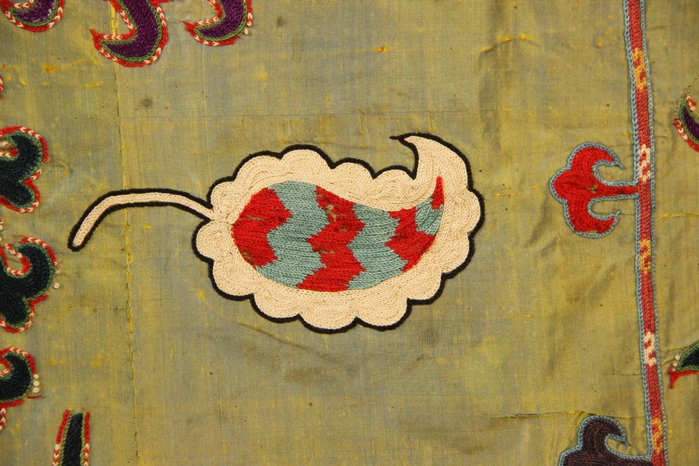 A rectangular green silk embroidered Suzani panel featuring a central circular solar motif flanked by intricate scrolling vines, botanical borders, and fringe edging. View VIII
