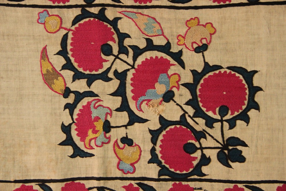 A rectangular hand-embroidered textile featuring central circular pomegranate motifs in crimson silk on a cream ground, framed by a floral border. View XI