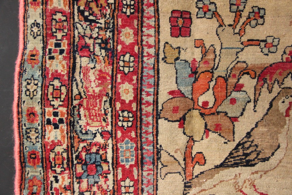 An antique hand-knotted Kirman Lavar wool rug featuring a central tree of life motif with birds and floral elements set on a cream field with a red border. View VII