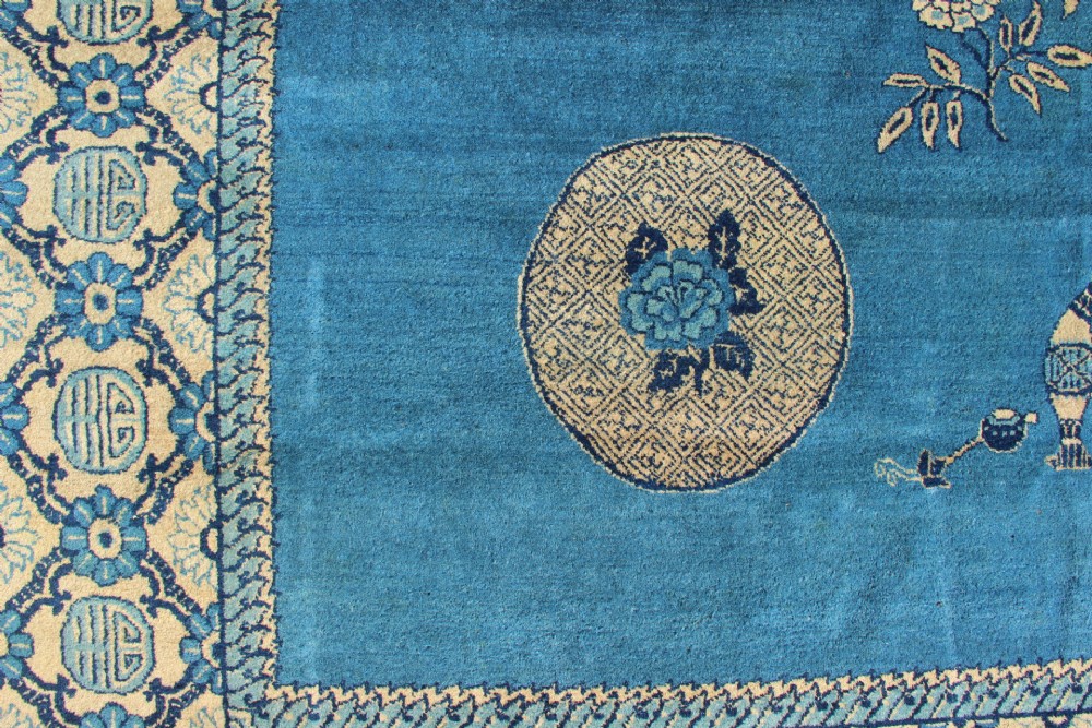 A large rectangular antique Chinese wool carpet featuring a vibrant blue field decorated with circular roundels and floral motifs, enclosed by a wide beige decorative border. View II