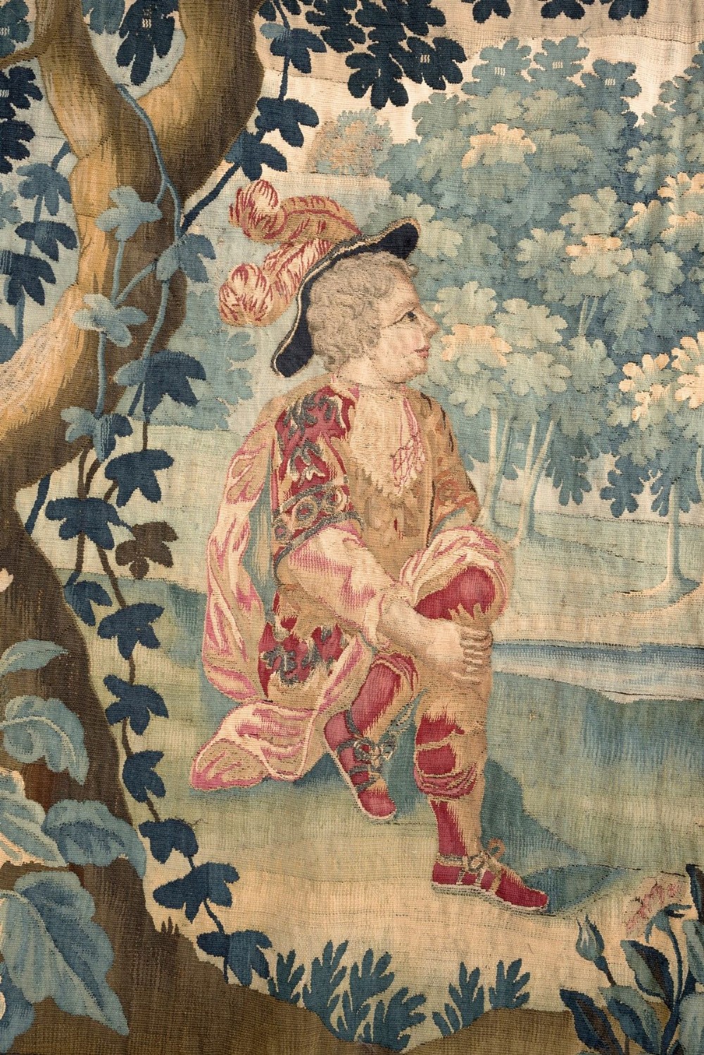 An 18th-century Audenaarde woven tapestry depicting two figures in a wooded landscape with a floral border. View III