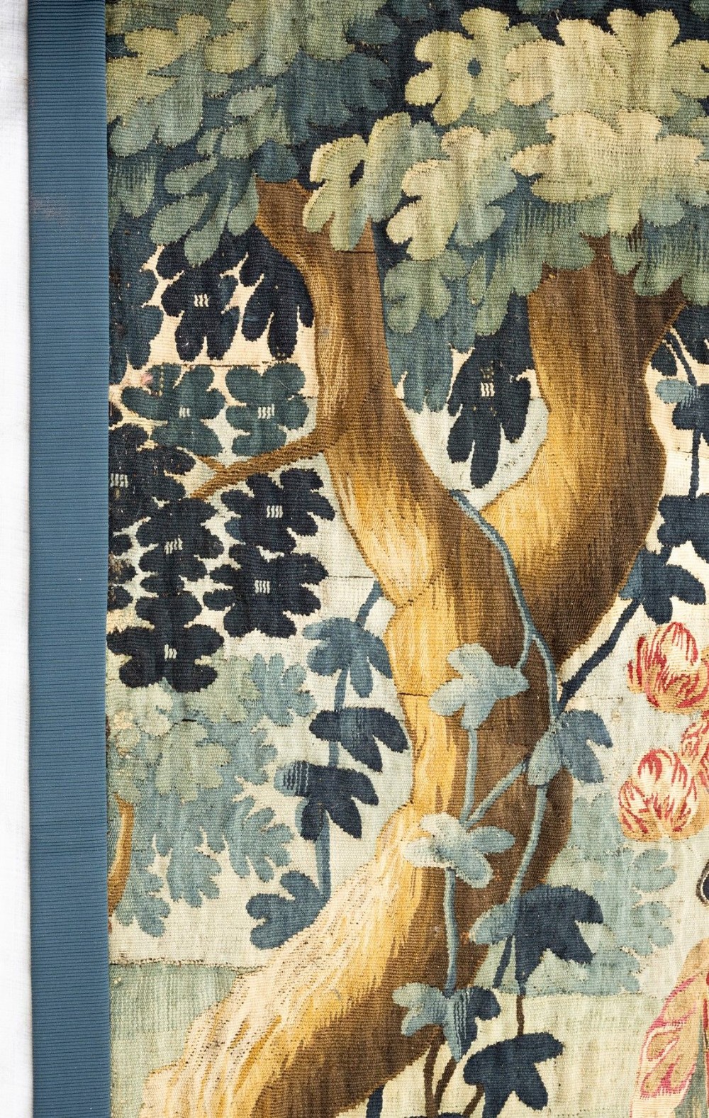 An 18th-century Audenaarde woven tapestry depicting two figures in a wooded landscape with a floral border. View V