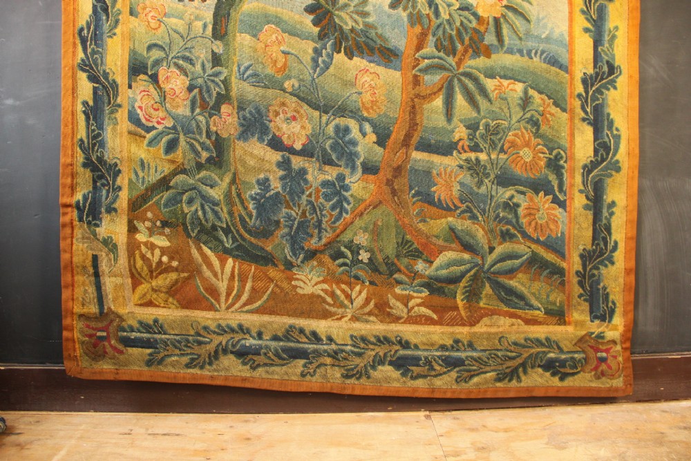 An 18th-century European needlework tapestry depicting lush botanical trees, perched birds, and floral motifs surrounded by a decorative foliate border. View III