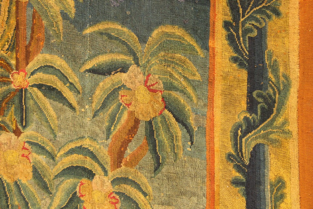 An 18th-century European needlework tapestry depicting lush botanical trees, perched birds, and floral motifs surrounded by a decorative foliate border. View VII
