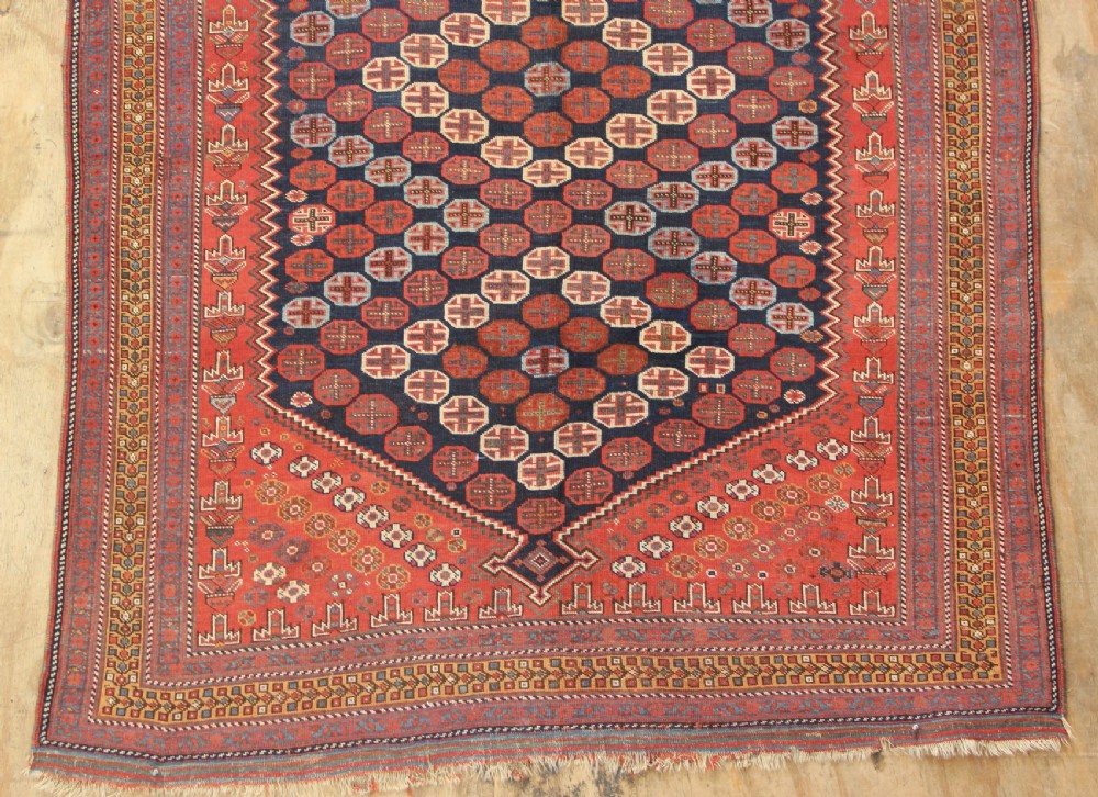 A hand-knotted rectangular wool carpet featuring a dark navy blue hexagonal field adorned with repeating geometric lattice motifs, surrounded by a bold terracotta red border. View II