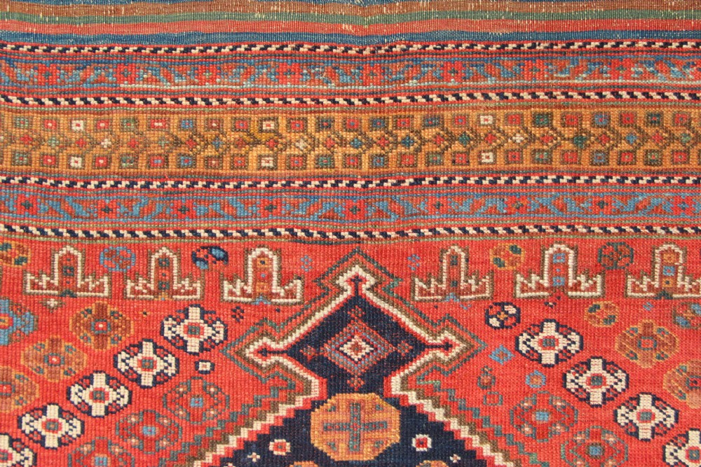 A hand-knotted rectangular wool carpet featuring a dark navy blue hexagonal field adorned with repeating geometric lattice motifs, surrounded by a bold terracotta red border. View X