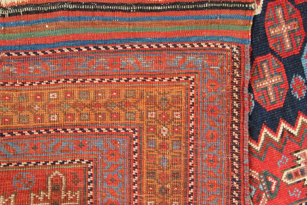 A hand-knotted rectangular wool carpet featuring a dark navy blue hexagonal field adorned with repeating geometric lattice motifs, surrounded by a bold terracotta red border. View XII