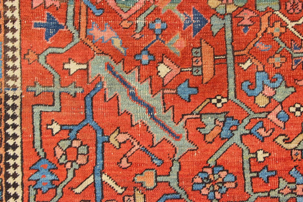 An antique hand-knotted Persian Bakshaish wool carpet featuring a central geometric motif on a terracotta red field framed by a wide blue floral border. View III