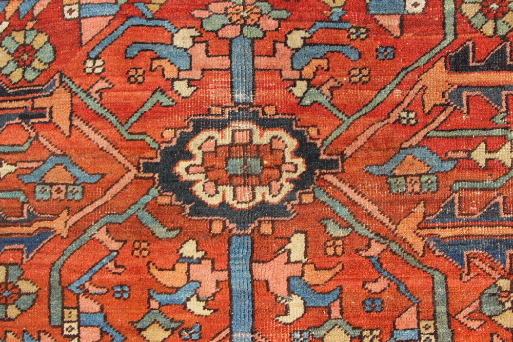 An antique hand-knotted Persian Bakshaish wool carpet featuring a central geometric motif on a terracotta red field framed by a wide blue floral border. View IV