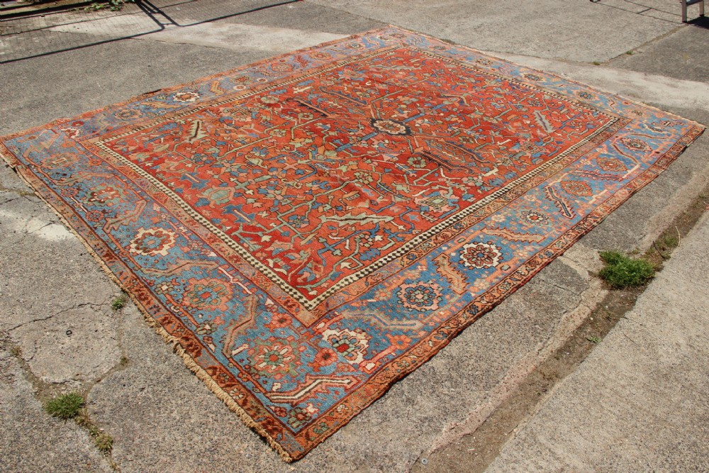An antique hand-knotted Persian Bakshaish wool carpet featuring a central geometric motif on a terracotta red field framed by a wide blue floral border. View XI