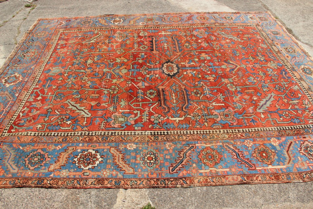 An antique hand-knotted Persian Bakshaish wool carpet featuring a central geometric motif on a terracotta red field framed by a wide blue floral border. View XII