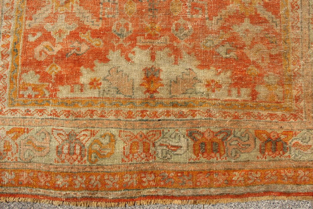 A large hand-woven 19th-century Ghiordes Oushak wool carpet featuring a central diamond medallion, intricate geometric borders, and a terracotta and pale green palette. View III