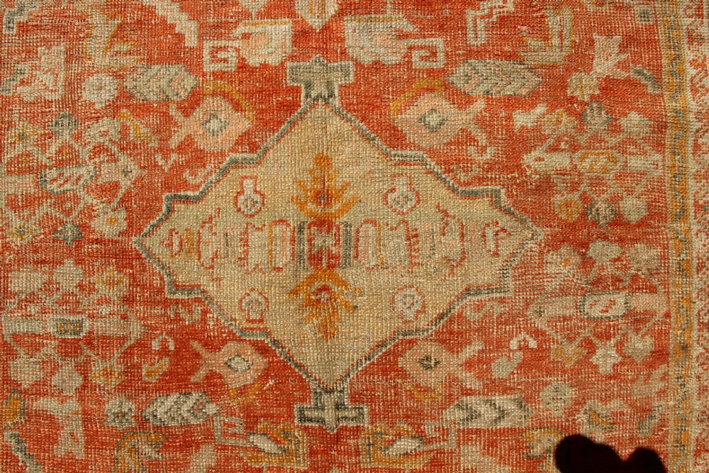 A large hand-woven 19th-century Ghiordes Oushak wool carpet featuring a central diamond medallion, intricate geometric borders, and a terracotta and pale green palette. View V