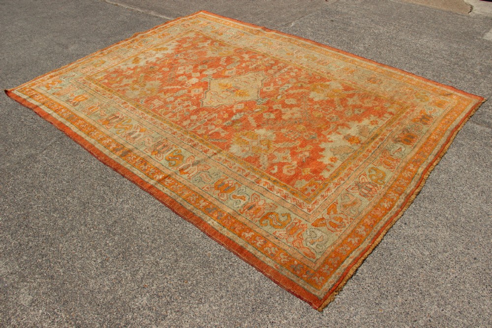 A large hand-woven 19th-century Ghiordes Oushak wool carpet featuring a central diamond medallion, intricate geometric borders, and a terracotta and pale green palette. View VIII