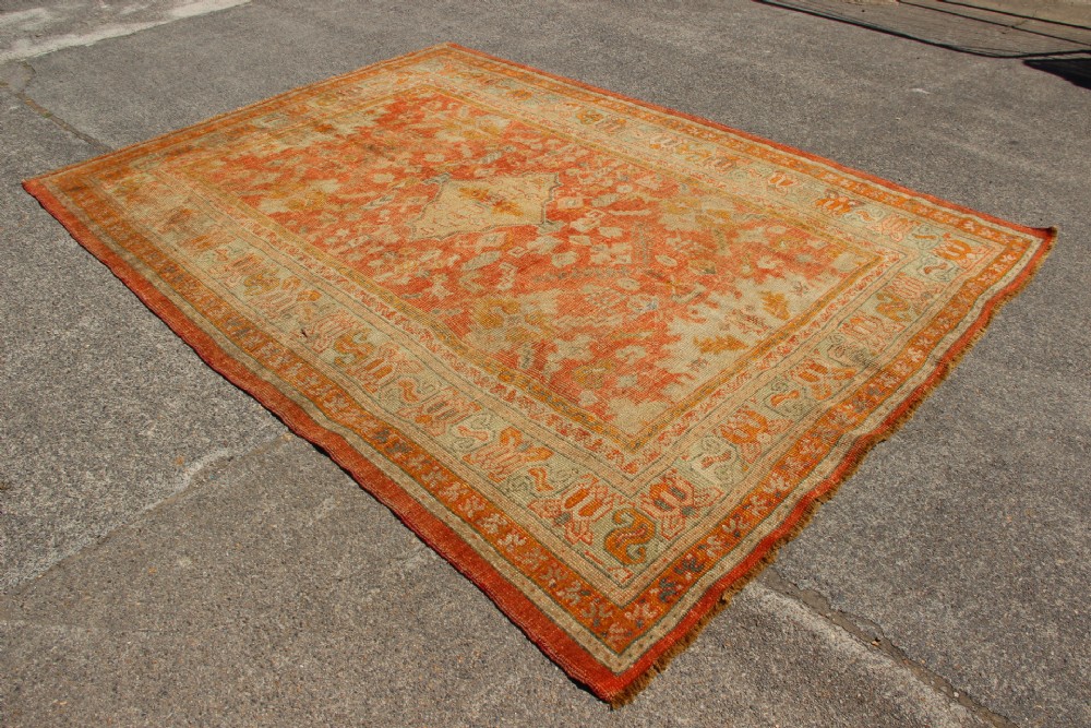 A large hand-woven 19th-century Ghiordes Oushak wool carpet featuring a central diamond medallion, intricate geometric borders, and a terracotta and pale green palette. View XI