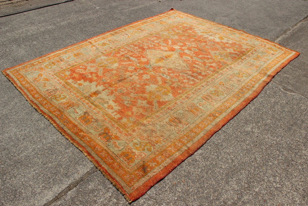 A large hand-woven 19th-century Ghiordes Oushak wool carpet featuring a central diamond medallion, intricate geometric borders, and a terracotta and pale green palette. View XIII