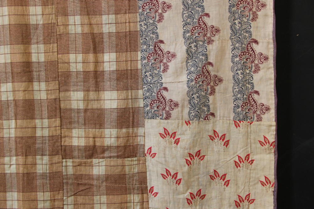 A rectangular hand-embroidered suzani textile featuring crimson floral motifs and blue scrolling vines on a cream ground. View X
