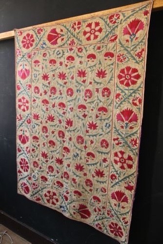 A rectangular hand-embroidered suzani textile featuring crimson floral motifs and blue scrolling vines on a cream ground. View VIII
