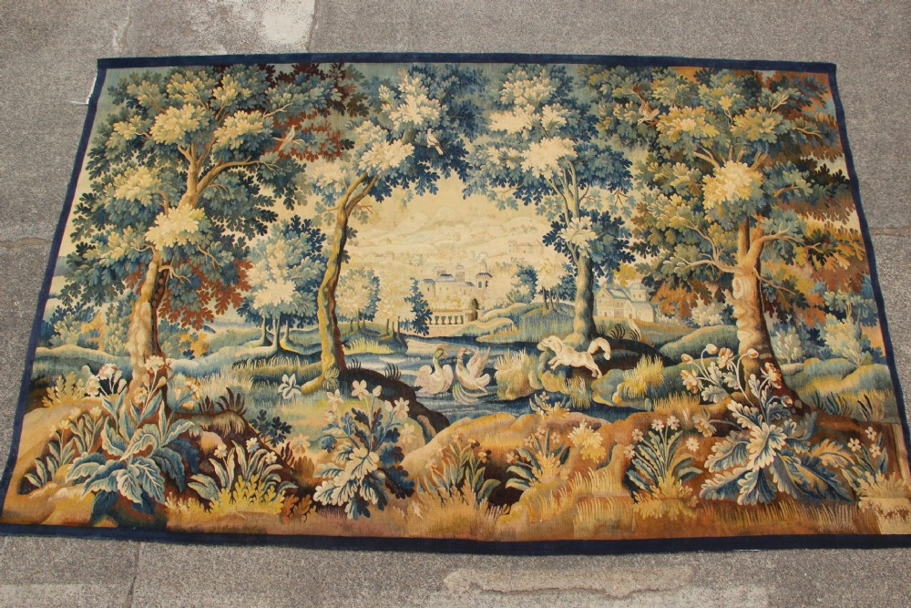 A large hand-woven French Aubusson verdure tapestry depicting swans swimming on a woodland river surrounded by trees and foliage.