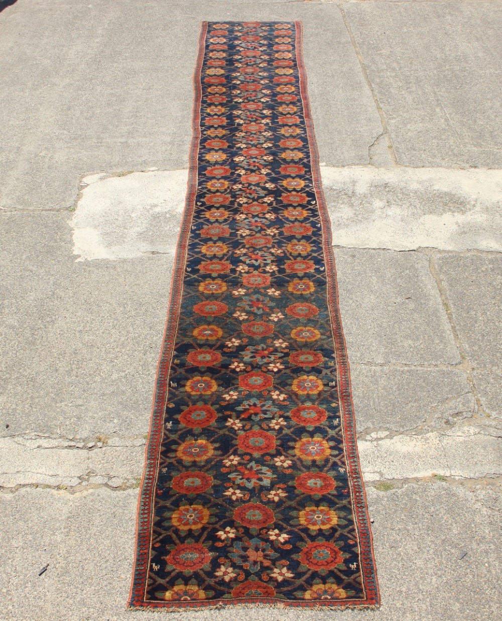 An extra-long hand-knotted antique Kurdish runner rug featuring a repeating Mina Khani floral lattice pattern in navy blue, rust red, and mustard yellow.