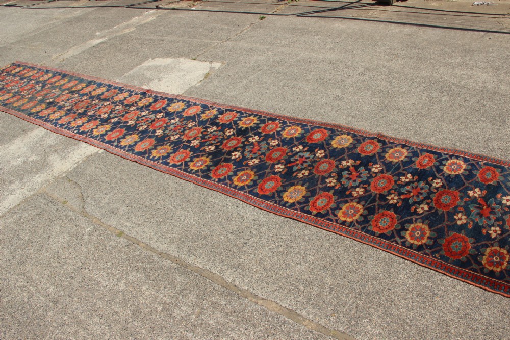 An extra-long hand-knotted antique Kurdish runner rug featuring a repeating Mina Khani floral lattice pattern in navy blue, rust red, and mustard yellow. View II