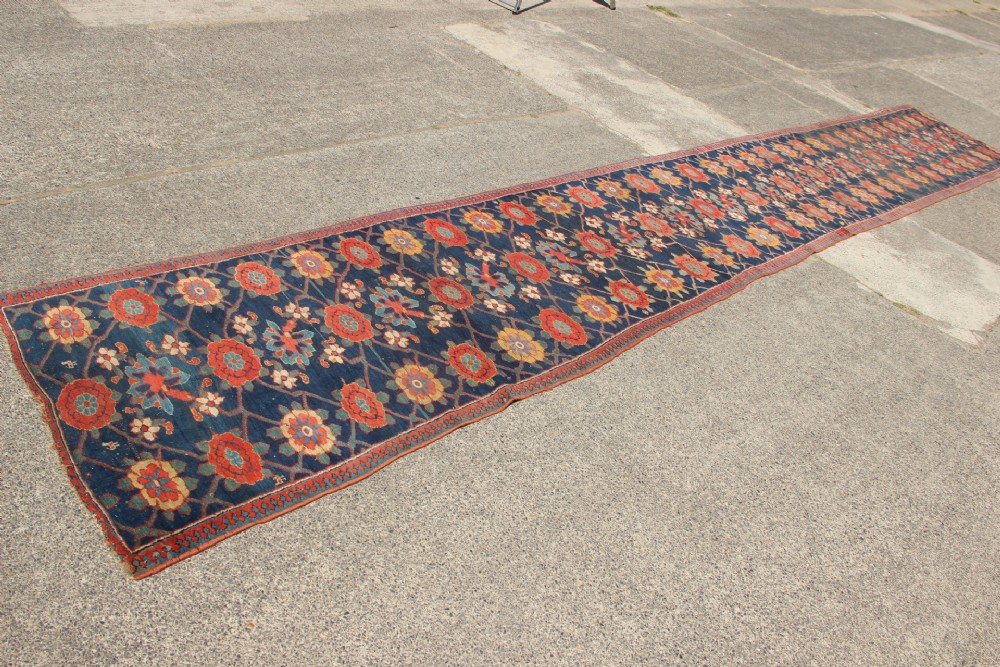 An extra-long hand-knotted antique Kurdish runner rug featuring a repeating Mina Khani floral lattice pattern in navy blue, rust red, and mustard yellow. View III
