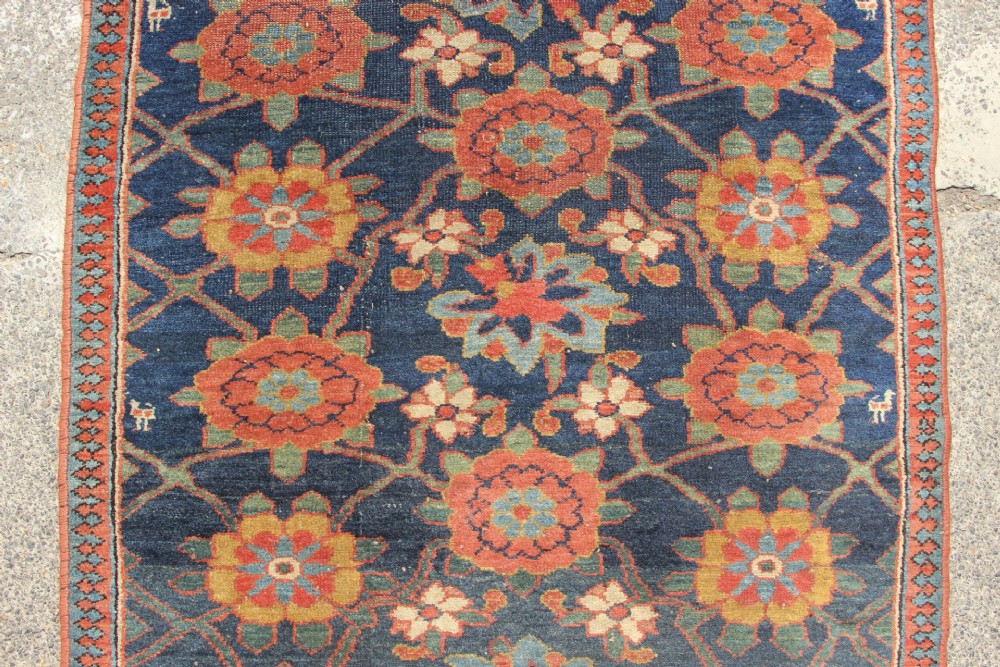 An extra-long hand-knotted antique Kurdish runner rug featuring a repeating Mina Khani floral lattice pattern in navy blue, rust red, and mustard yellow. View VI