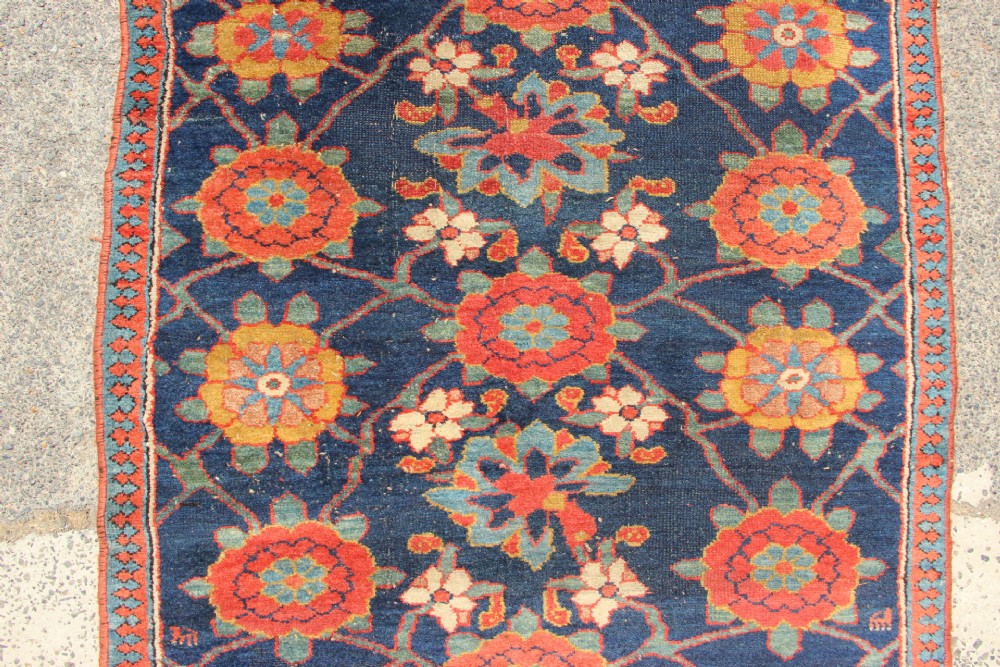 An extra-long hand-knotted antique Kurdish runner rug featuring a repeating Mina Khani floral lattice pattern in navy blue, rust red, and mustard yellow. View VII
