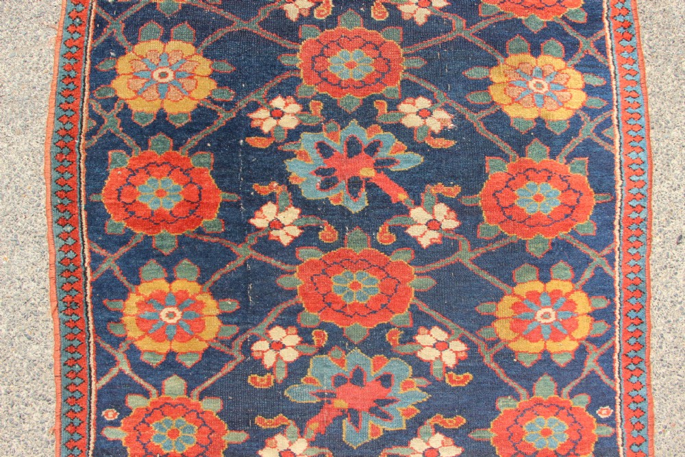 An extra-long hand-knotted antique Kurdish runner rug featuring a repeating Mina Khani floral lattice pattern in navy blue, rust red, and mustard yellow. View VIII
