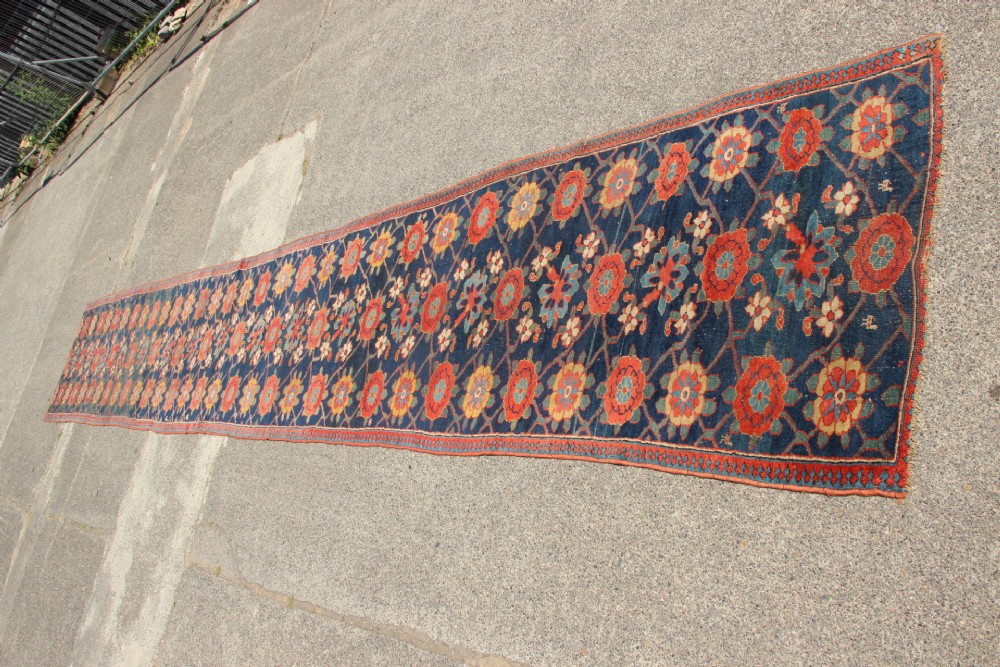 An extra-long hand-knotted antique Kurdish runner rug featuring a repeating Mina Khani floral lattice pattern in navy blue, rust red, and mustard yellow. View XI