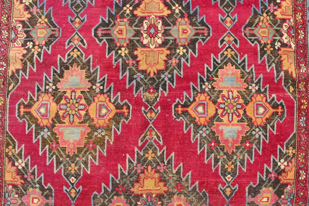An antique Caucasian Karabagh carpet with a crimson red field displaying stepped geometric medallions framed by a sky blue border. View XIII