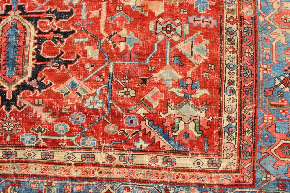 An antique Persian Bakshaish wool carpet featuring a terracotta red field with geometric central motifs enclosed by a light blue patterned border. View XIV