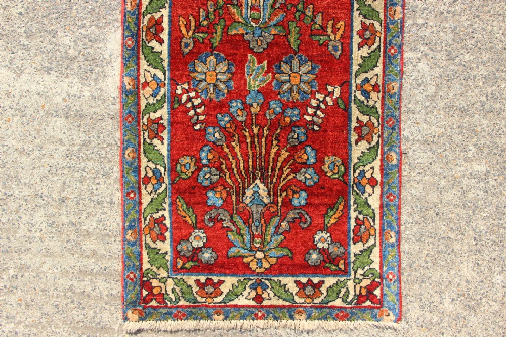 An antique hand-knotted Persian Sarouk rug runner featuring a vibrant crimson field decorated with floral motifs within a patterned border. View II